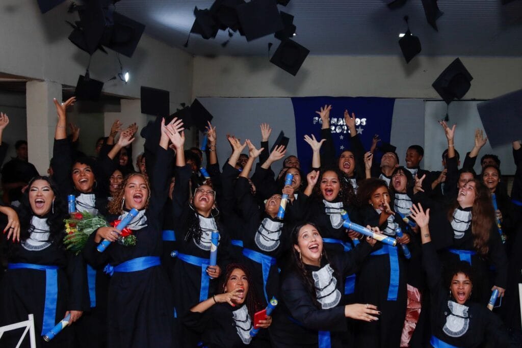 Turma de formandos com faixa azul comemorando no encerramento da cerimônia