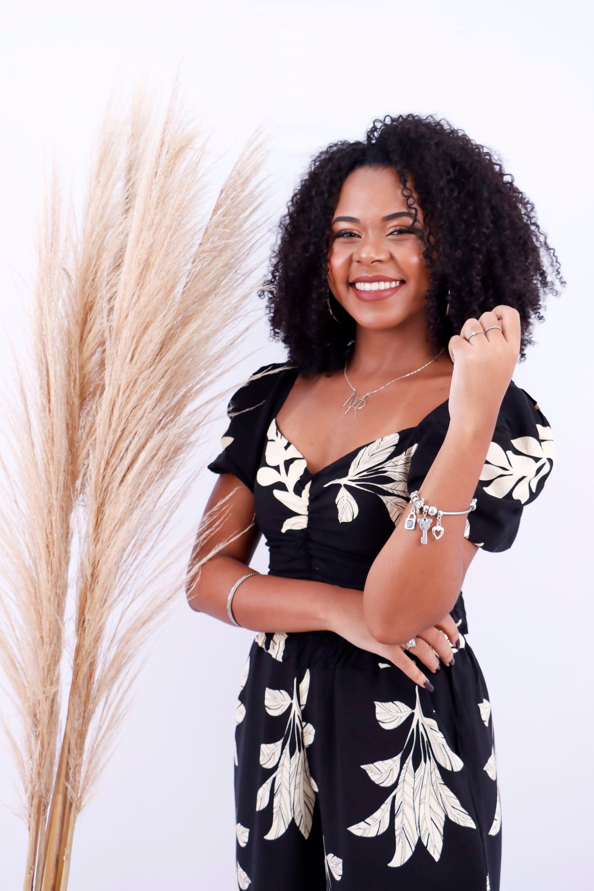 Cantora sorrindo ao lado de plumas secas, mostrando a pulseira
