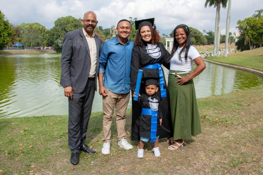 Formanda de Administração do Senac com a família e o filho pequeno de beca segurando o canudo, na Quinta da Boa Vista