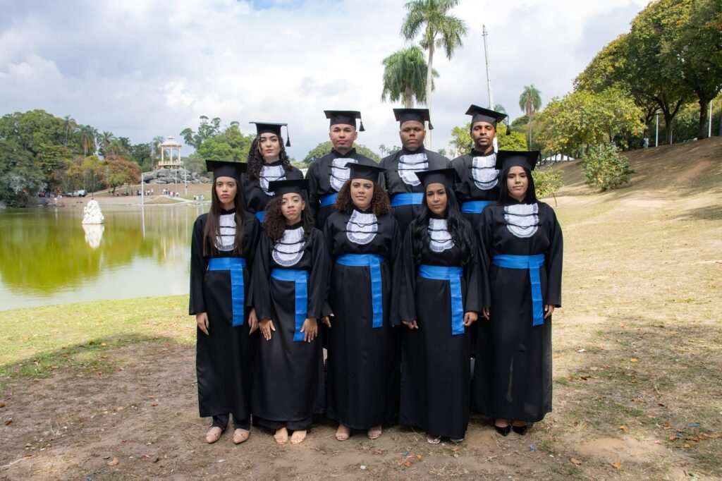 Turma de Administração do Senac de beca e faixa azul em duas fileiras à beira do lago da Quinta da Boa Vista