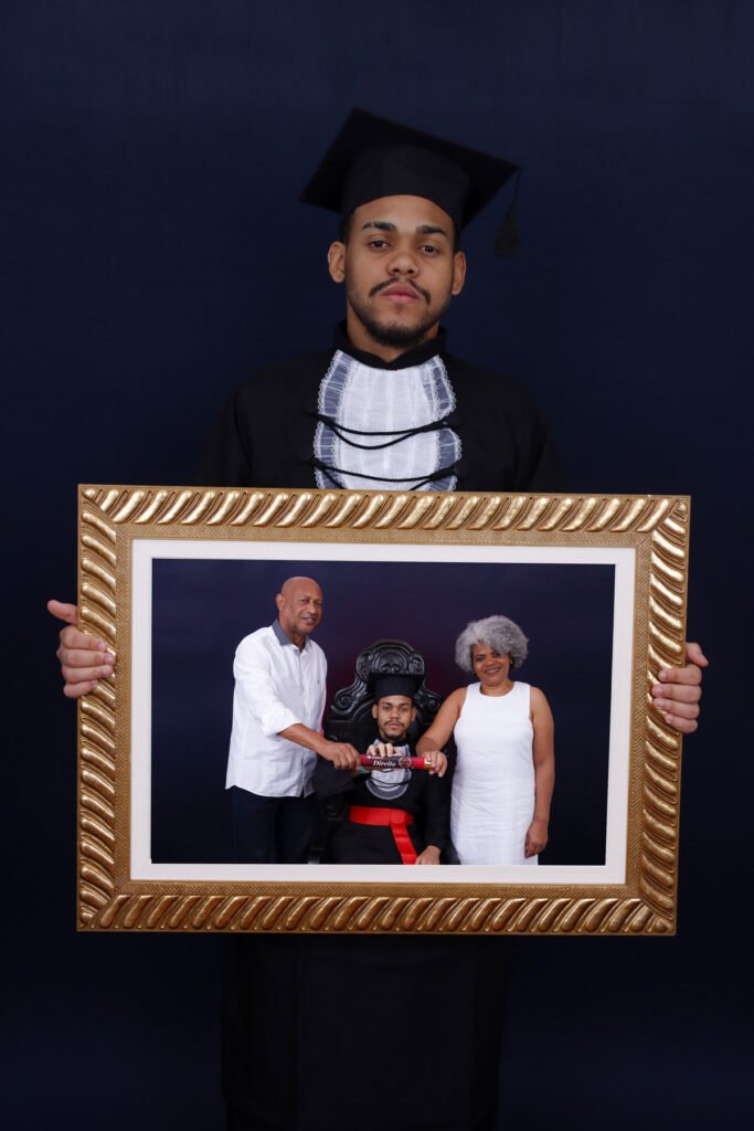 Formando de Direito segurando uma moldura dourada com a foto dele com a família