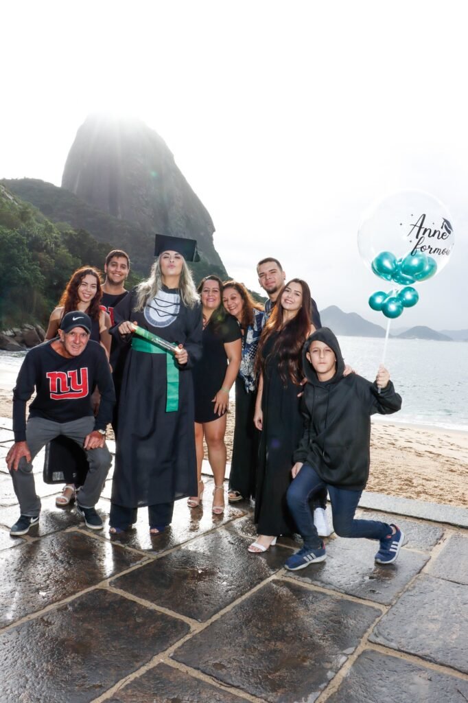 Formanda de Enfermagem com a família e um balão de comemoração na Praia Vermelha, com o Pão de Açúcar ao fundo