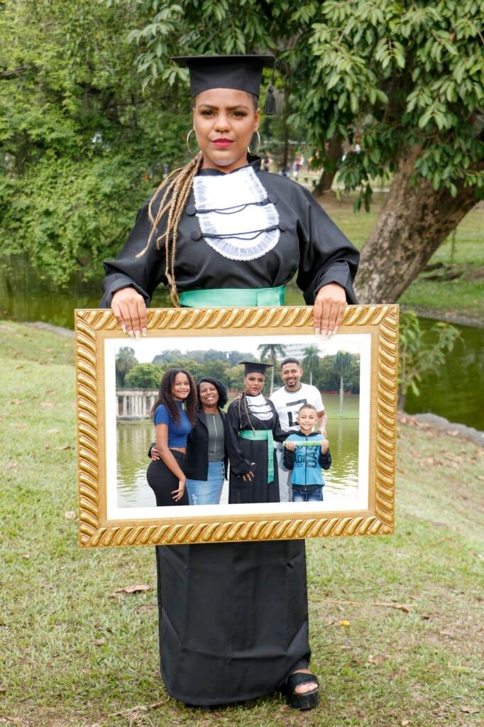 Formanda de Enfermagem segurando um quadro dourado com a foto da família feita no mesmo dia, na Quinta da Boa Vista