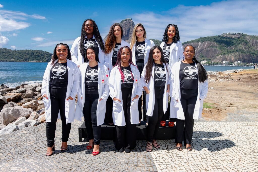 Turma de Análises Clínicas de jaleco branco e camiseta do curso à beira da baía, com o Pão de Açúcar ao fundo