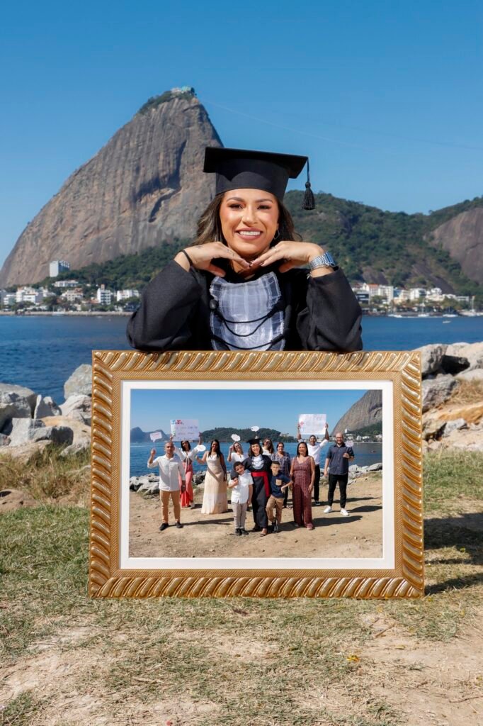 Formanda de Ciências Contábeis apoiada num quadro dourado com a foto da família, com o Pão de Açúcar ao fundo