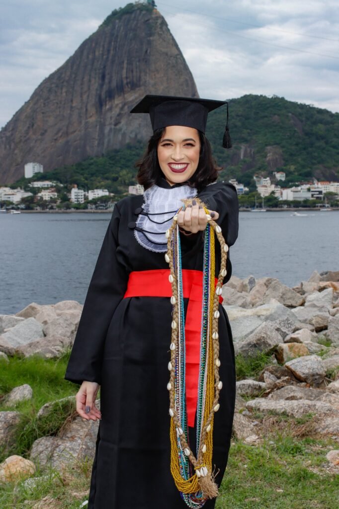 Formanda de Direito mostrando colares de contas e búzios, com o Pão de Açúcar ao fundo