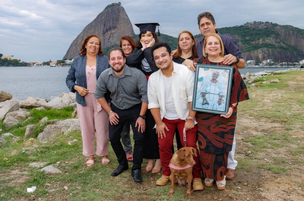 Formanda de Direito com a família, o cachorro e um retrato emoldurado, com o Pão de Açúcar ao fundo