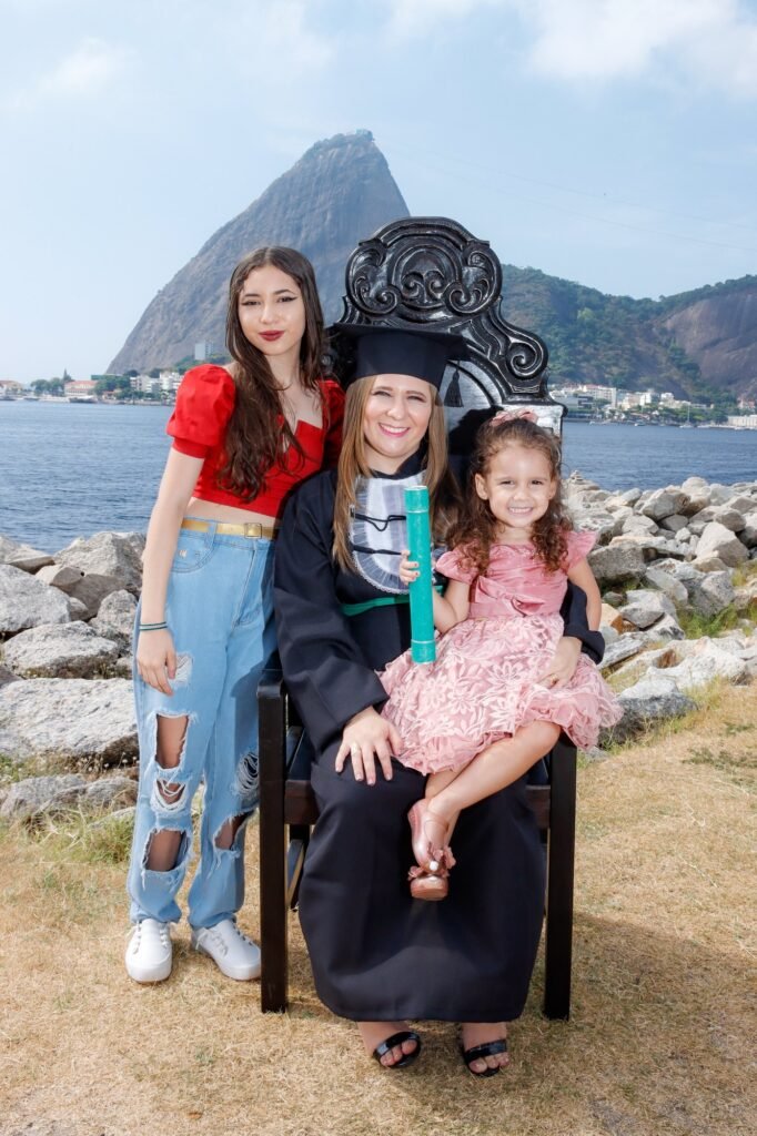 Formanda de Enfermagem na Cadeira Colonial Luiz XV com duas meninas da família e o canudo verde, com o Pão de Açúcar ao fundo