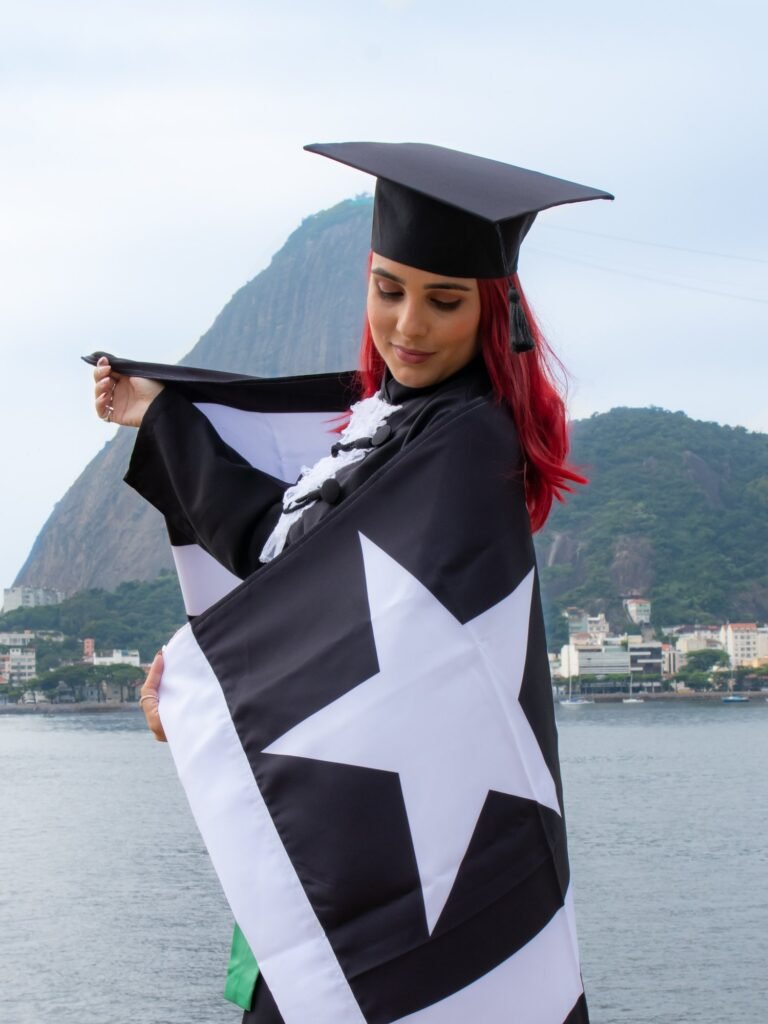Formanda de Optometria de cabelo vermelho envolta na bandeira do Botafogo, com o Pão de Açúcar ao fundo