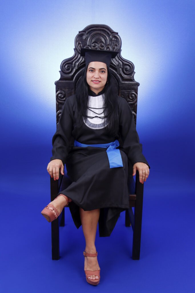 Formanda de Fotografia de beca e faixa azul sentada na Cadeira Colonial Luiz XV do estúdio