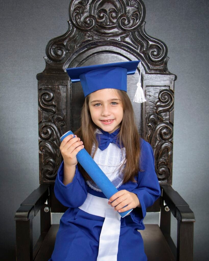 Criança de beca azul e capelo no ensaio de formatura infantil no estúdio do Z7 Studio