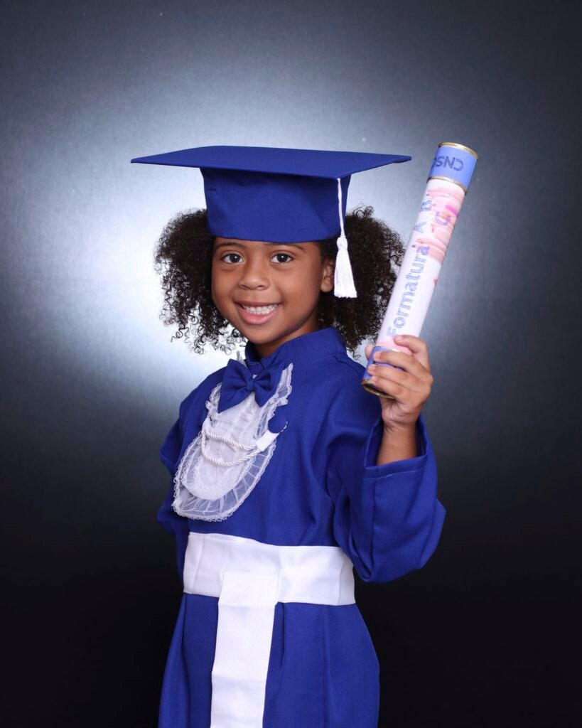 Menina de beca azul e capelo segurando o canudo da Formatura ABC