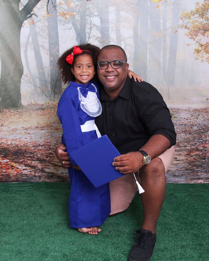 Pai e filha de beca azul no cenário de floresta do estúdio