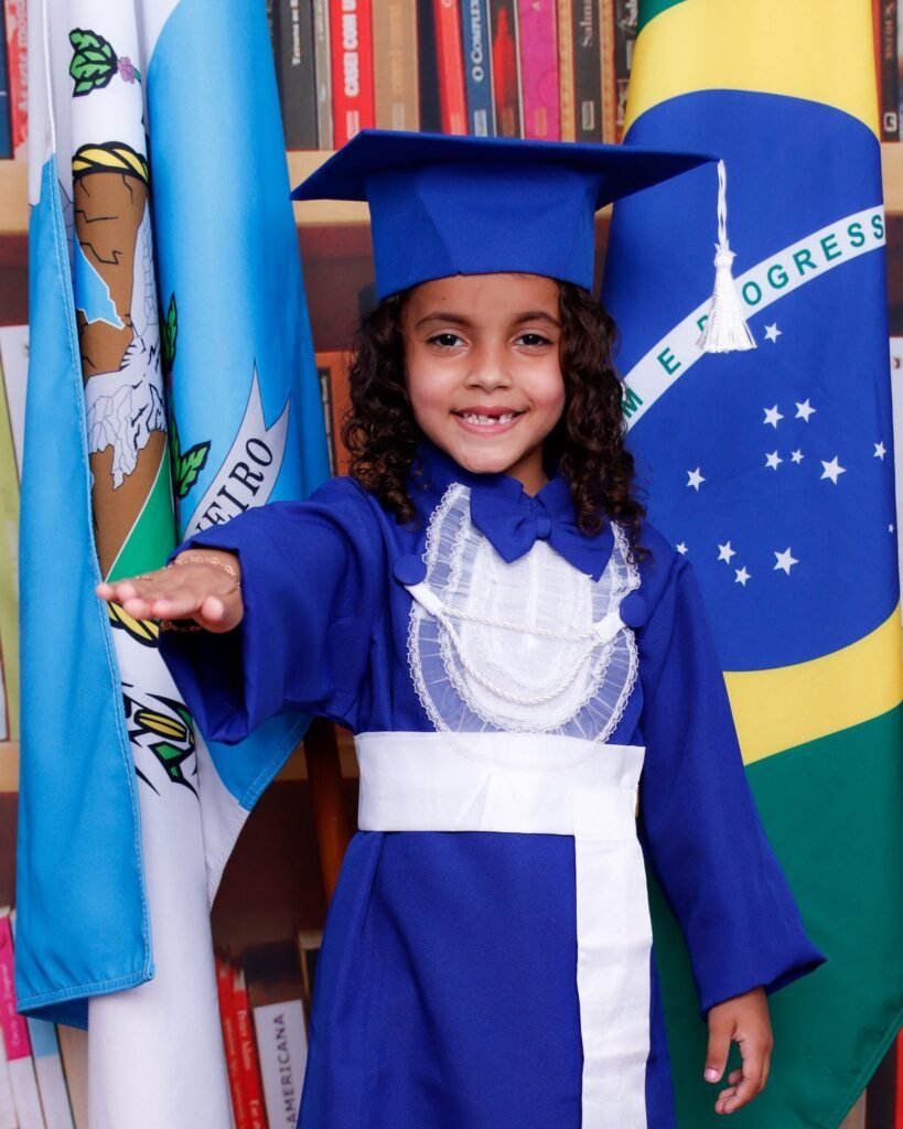 Menina de beca azul fazendo o juramento entre as bandeiras do Brasil e do estado do Rio