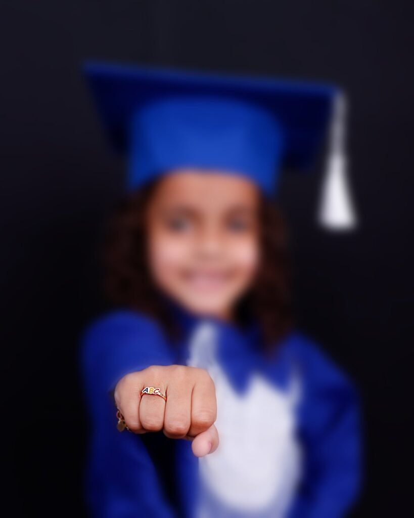 Menina de beca azul mostrando o anel ABC de formatura
