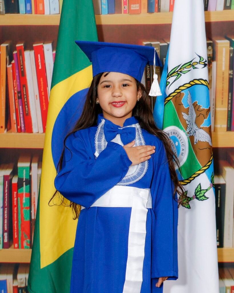 Menina de beca azul com a mão no peito entre as bandeiras do Brasil e do estado do Rio