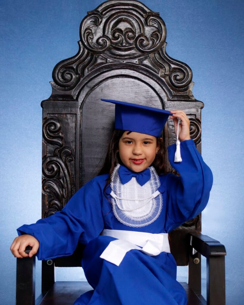 Menina de beca azul na cadeira entalhada segurando o capelo
