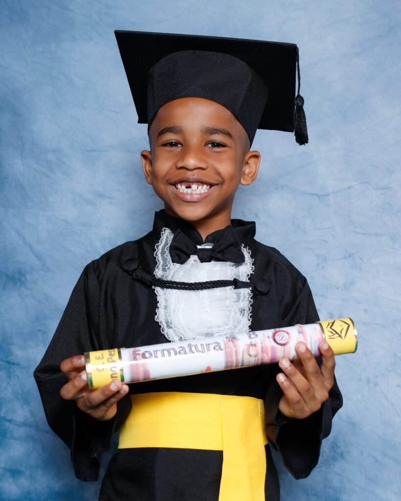 Menino de beca preta sorrindo com o canudo da Formatura ABC