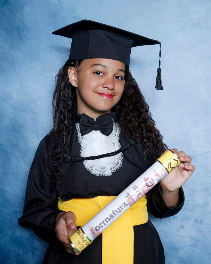 Menina de beca preta segurando o canudo da Formatura ABC