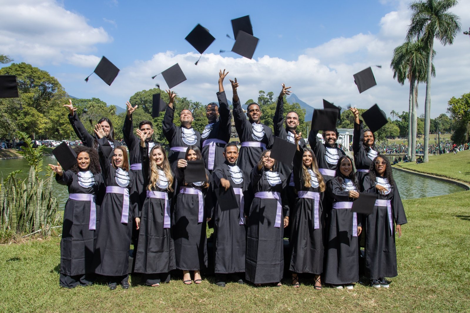 Turma de Química do IFRJ de faixa lilás jogando os capelos para o alto à beira do lago da Quinta da Boa Vista