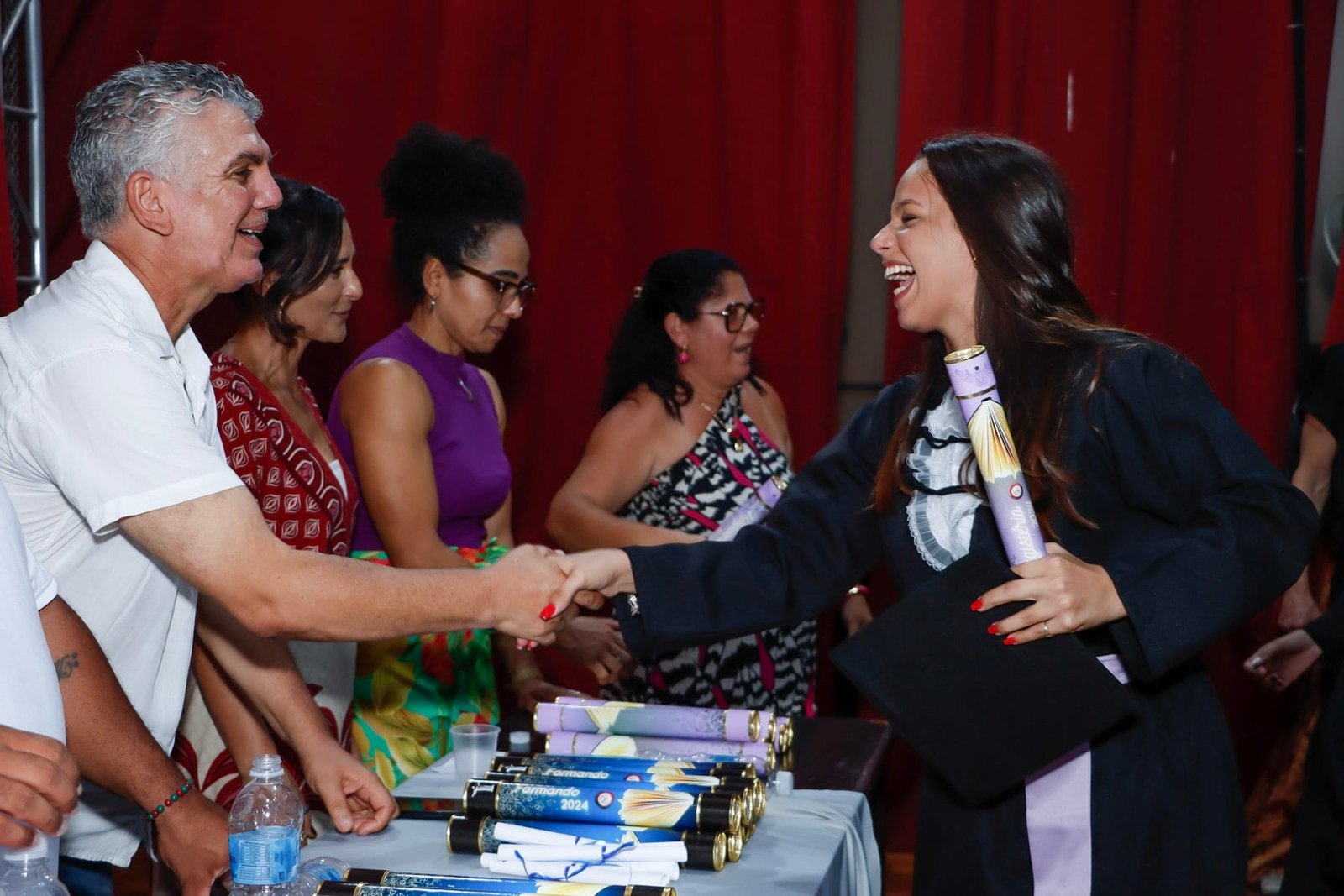 Formanda cumprimentando a mesa ao receber o diploma na colação de grau