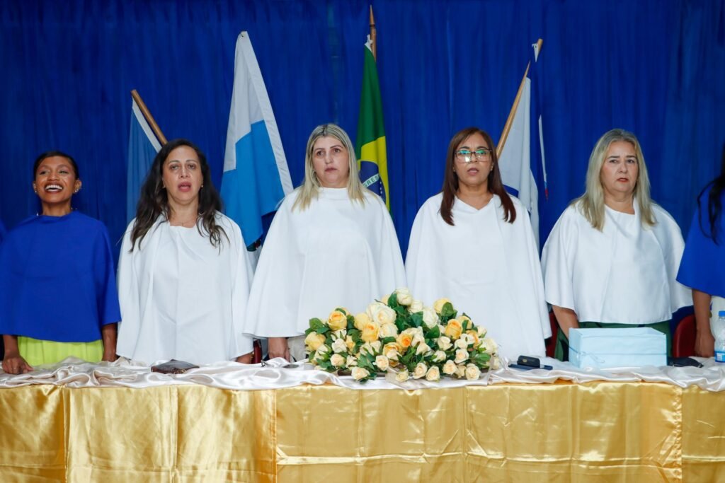 Mesa de honra da cerimônia de formatura com as bandeiras ao fundo